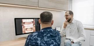 Dentysta omawia z pacjentem zdjęcia zębów wyświetlone na monitorze.